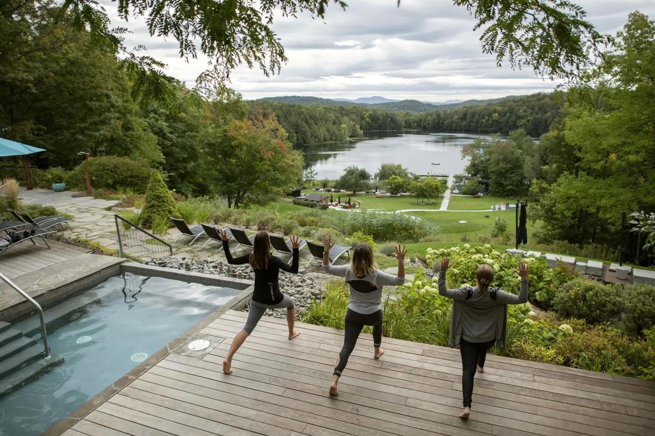 Three women practice yoga outdoors at Balnea Spa, a luxury wellness retreat in Québec's Eastern Townships.