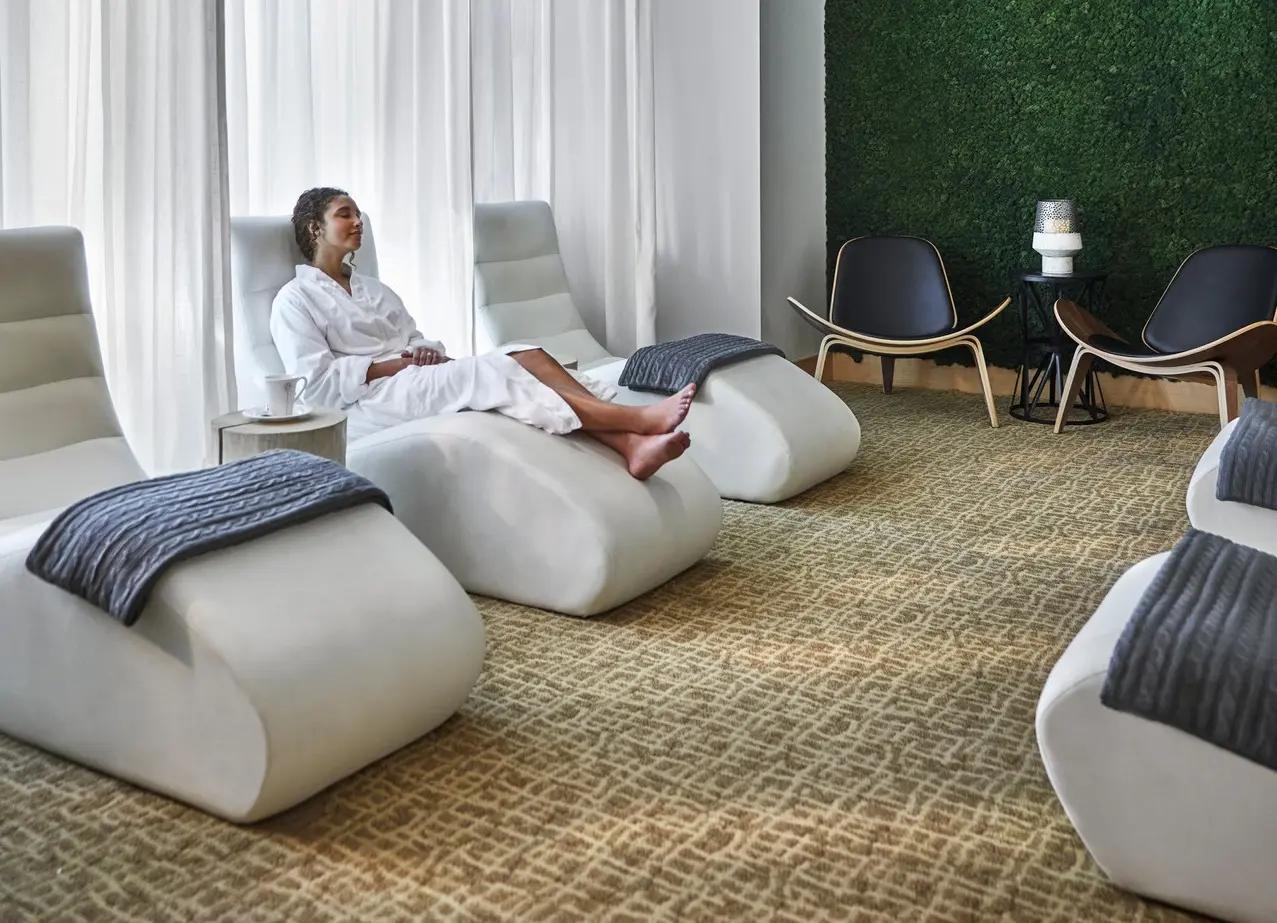 Woman relaxing in a white robe at The Spa at Four Seasons Resort Whistler, with living moss wall and natural light.