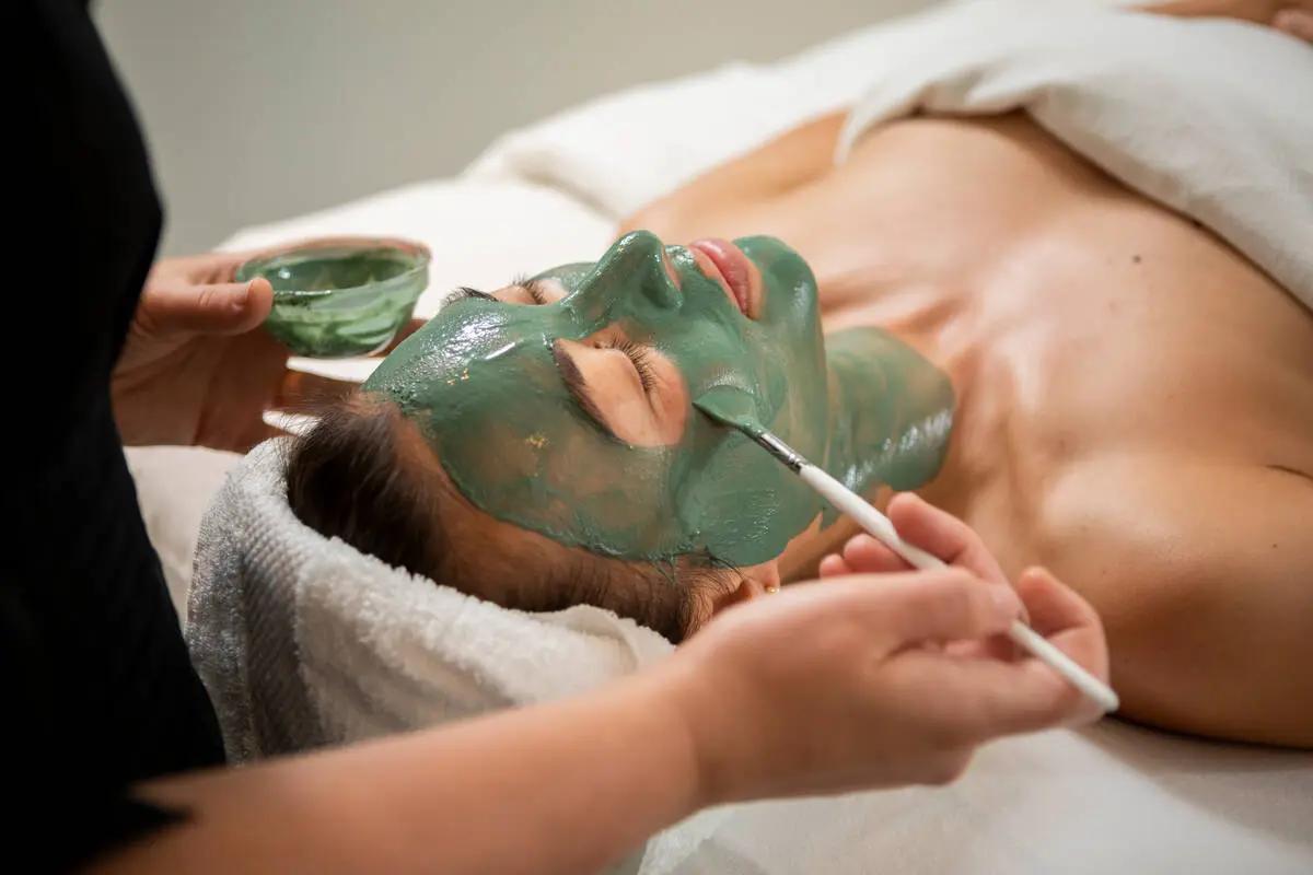 Spa therapist applying a green clay facial at The Spa at Nita Lake Lodge in Whistler's Creekside neighborhood.