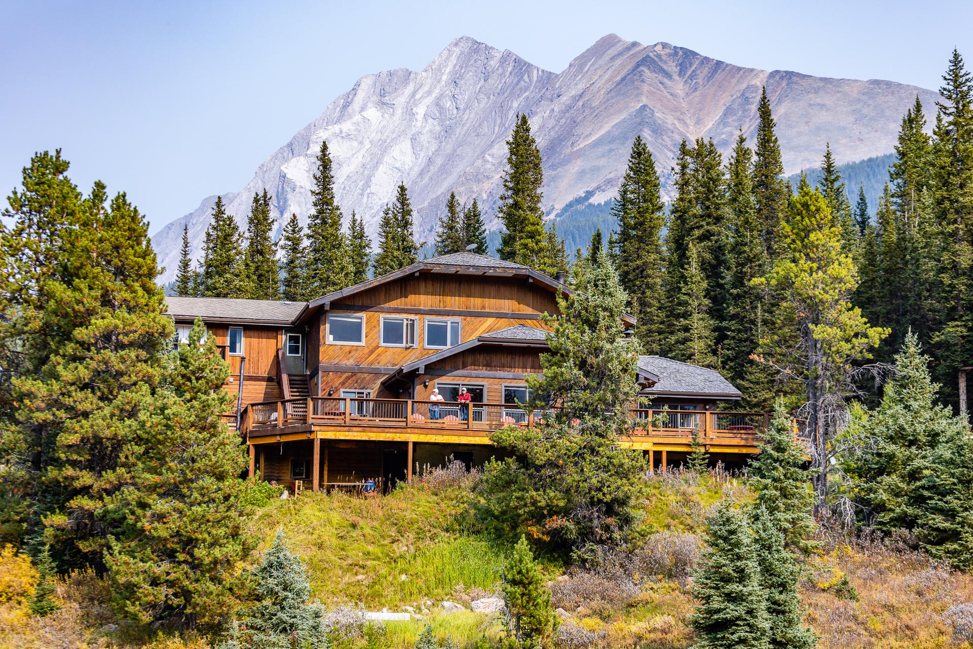 Mountain Engadine lodge surrounded by evergreen forest with rocky peaks rising in the background