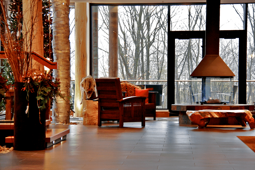 A warm, wood-accented lobby at Hôtel-Musée Premières Nations features birch columns, Indigenous crafts, and floor-to-ceiling windows overlooking the winter forest.