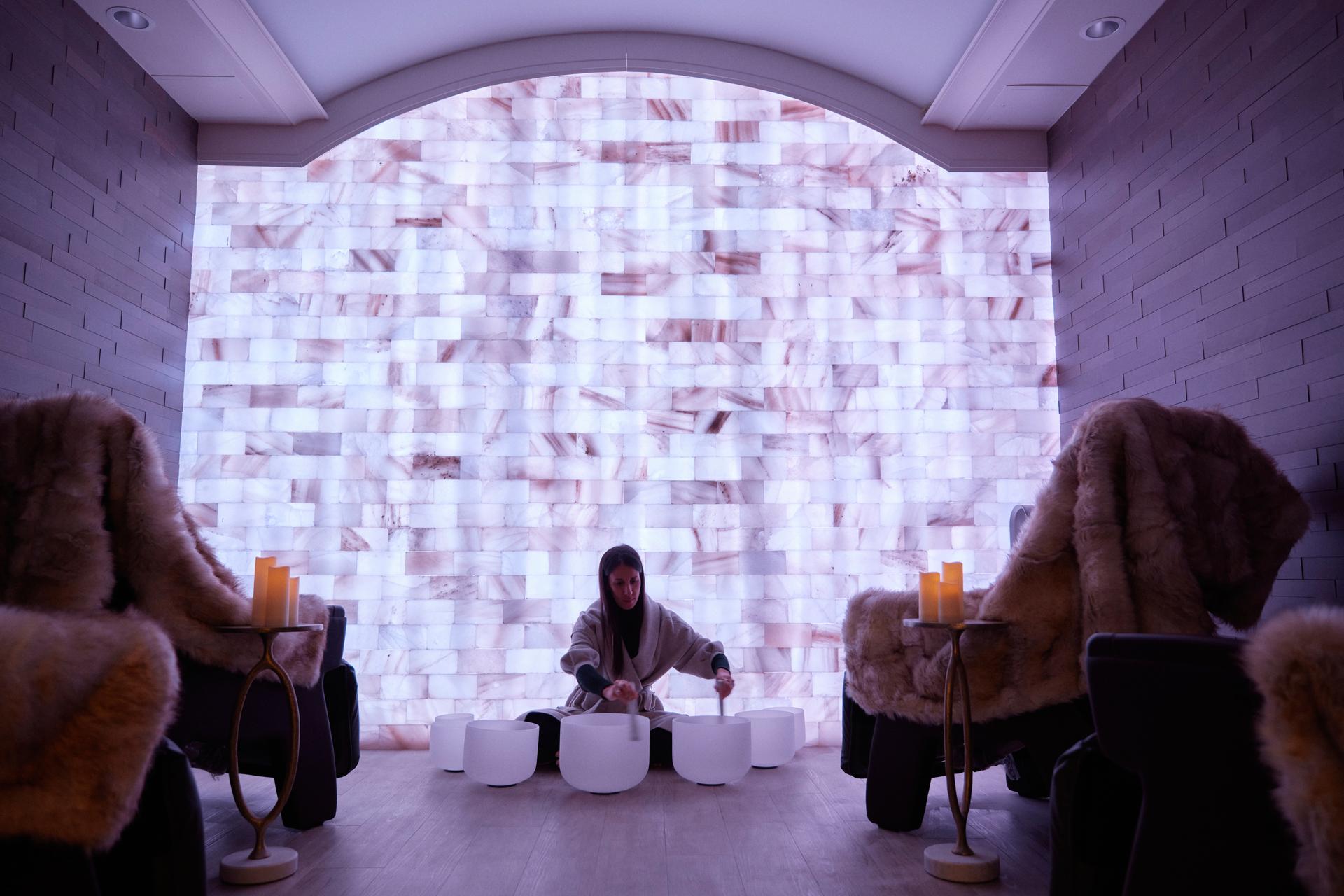 Guide playing crystal singing bowls during a guided sound bath session in the halotherapy lounge at Spa at Q, 124 on Queen Hotel, Niagara-on-the-Lake, Ontario