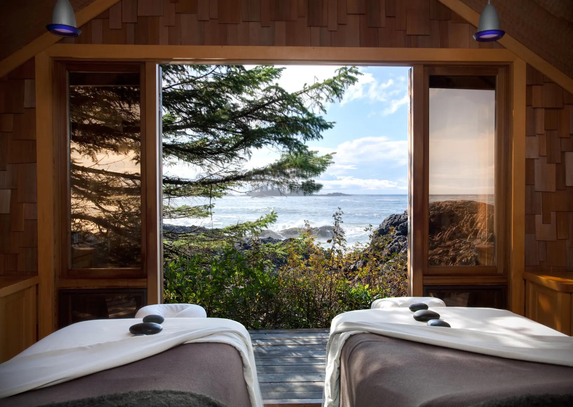 An ocean view through an open cedar-framed window. In the background, waves crash against the rocky shores of the Pacific coast.