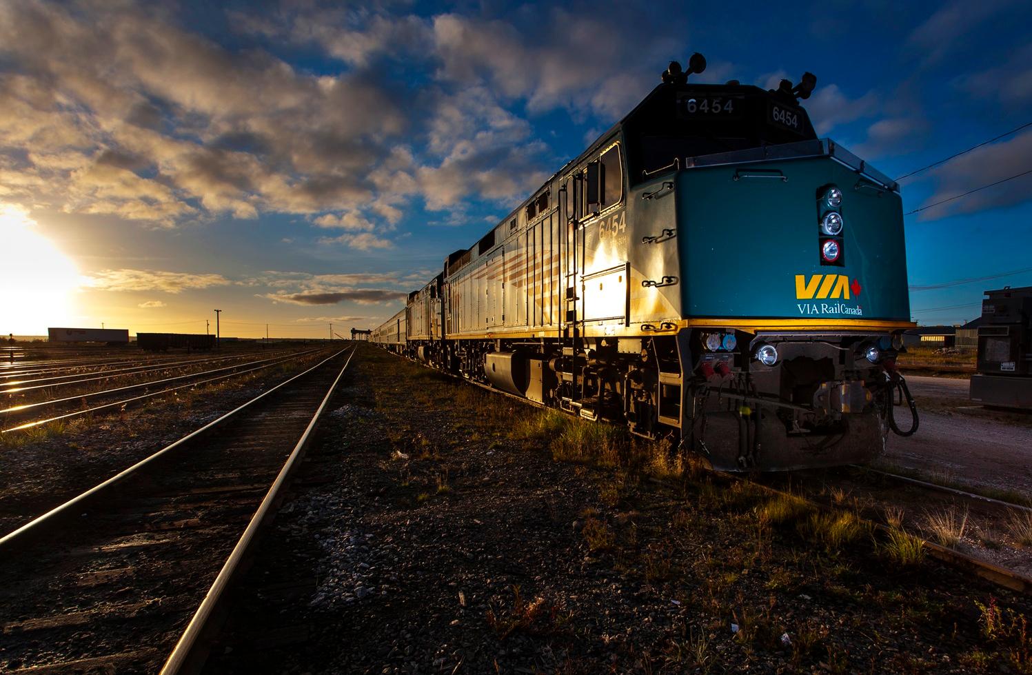 VIA Rail train on railway tracks at sunset