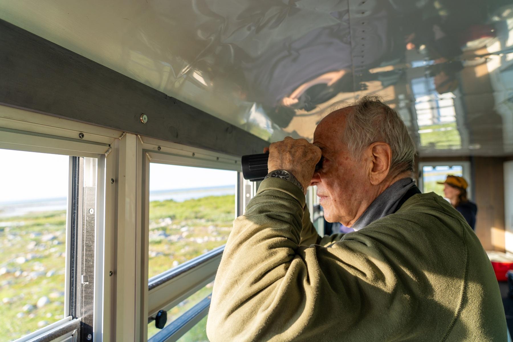 A person looking through binoculars from a tundra buggy