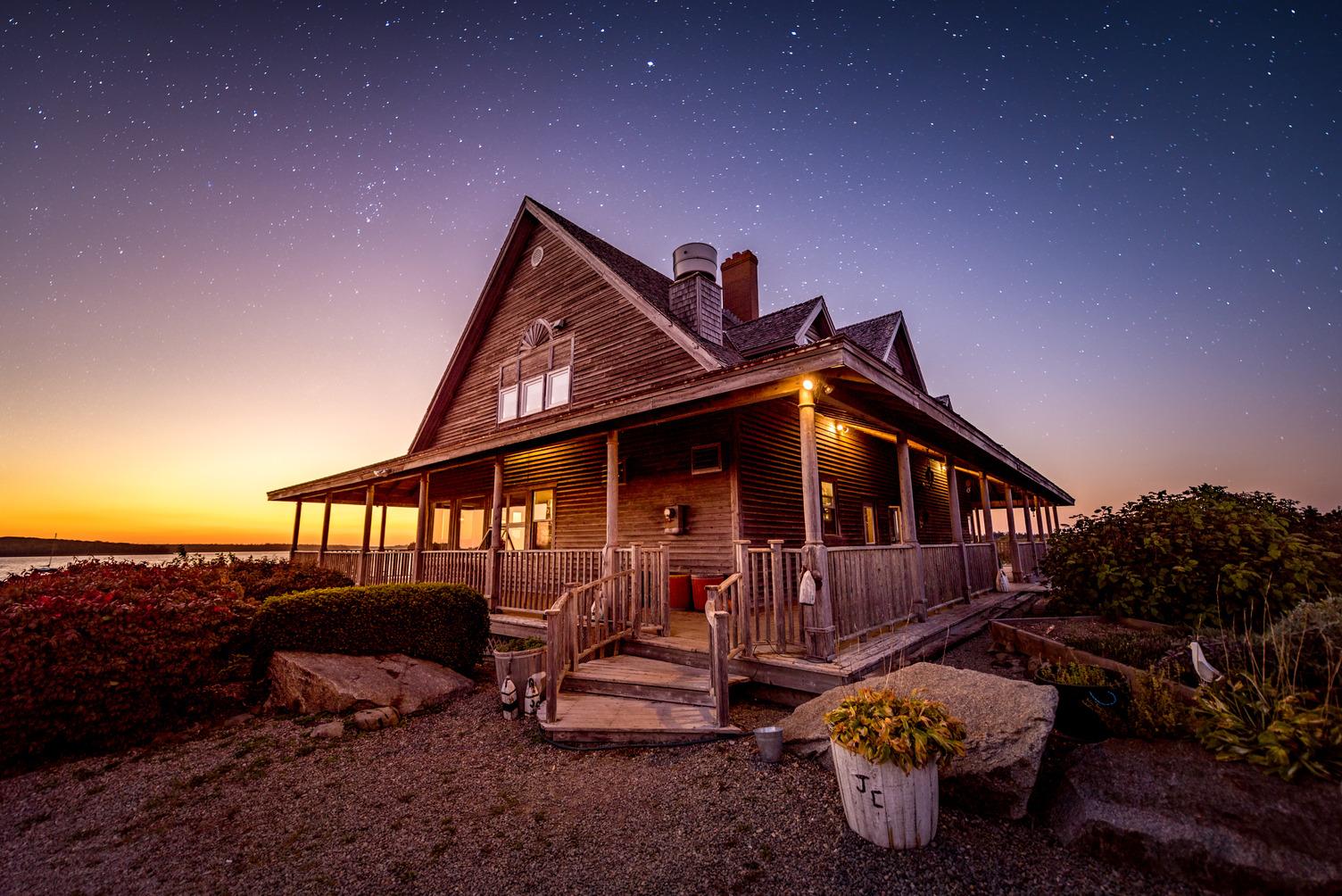Argyler Lodge, a wood-sided country inn on the Yarmouth and Acadian Shores, lit up beneath a star-filled sky at dusk.
