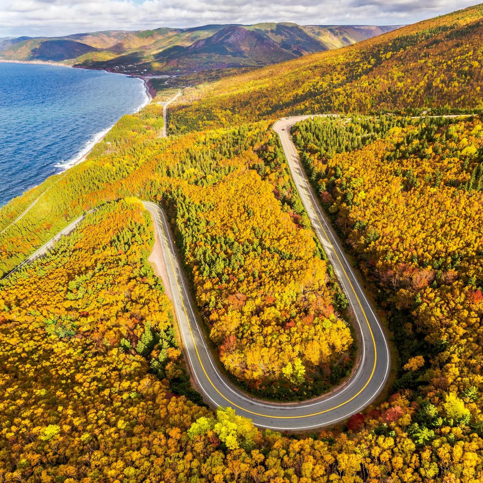 Aerial view of the Cabot Trail winding through autumn foliage along the coast of Cape Breton Island
