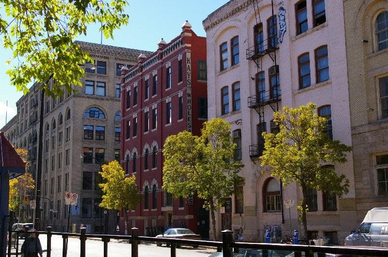 Exchange District in Winnipeg, Manitoba, showing early-1900s brick-and-stone warehouse buildings lining a tree-shaded street