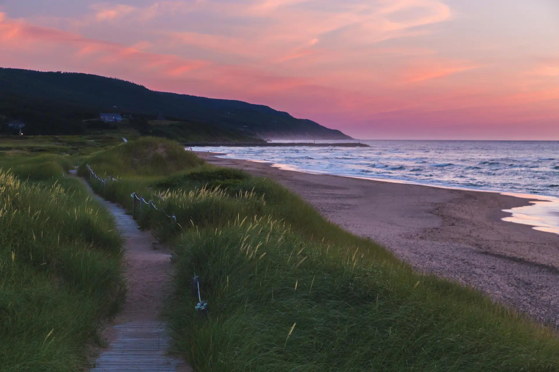 Boardwalk trail winding through grassy dunes to the beach at Inverness, Cape Breton Island, at sunset
