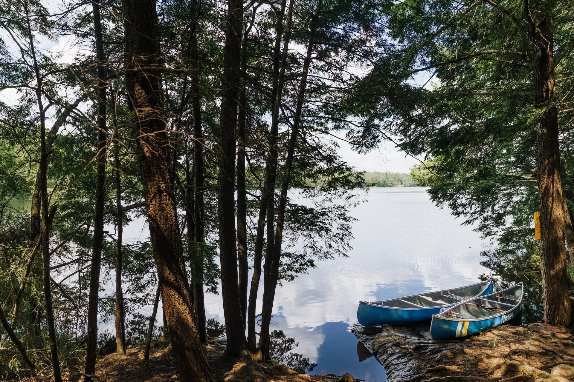 Two canoes beached on a granite outcrop along the Canadian Shield shoreline of Kawartha Highlands Provincial Park, a canoe-only camping destination in Ontario.