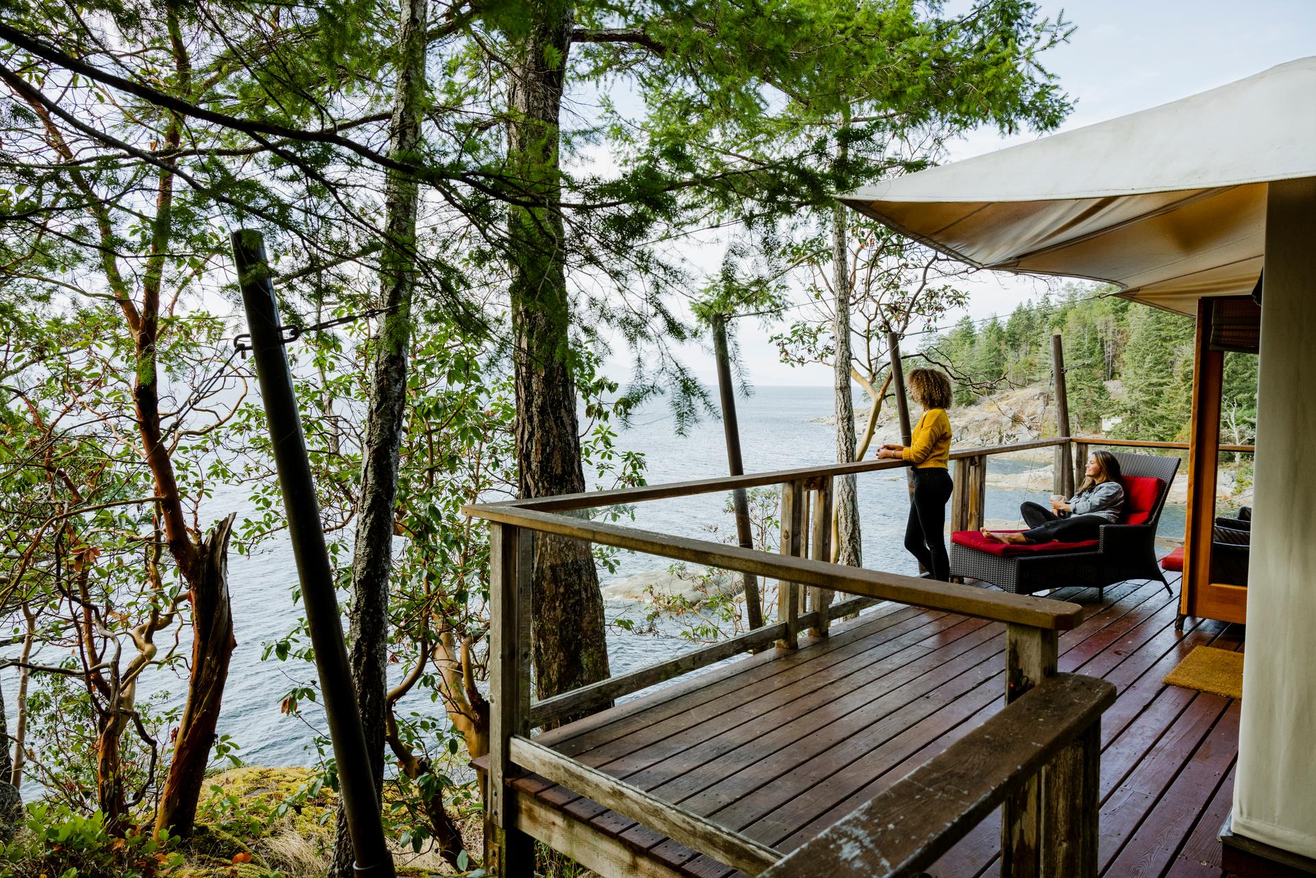 Two guests relax on the deck of a canvas tenthouse suite overlooking the ocean at Rockwater Secret Cove Resort in British Columbia