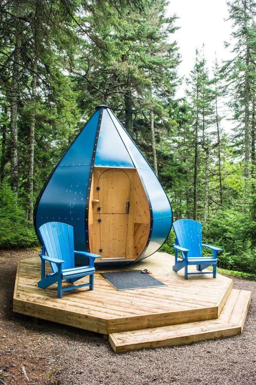 Close-up of the Teardrop Dwelling's wood-paneled door and blue steel exterior at Fundy National Park, New Brunswick