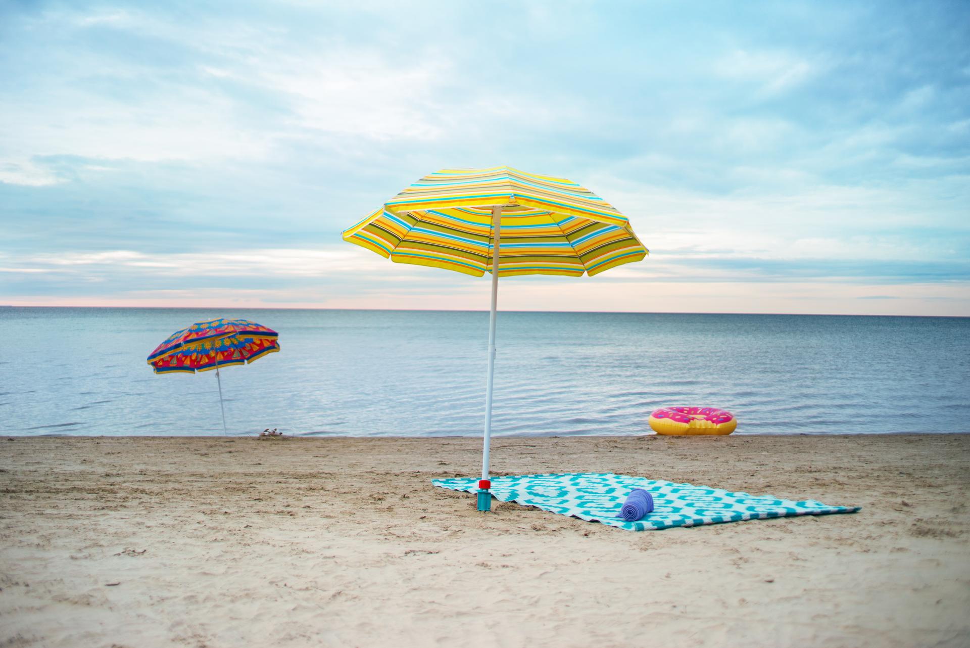 Striped beach umbrellas and a towel spread on the sand at Wasaga Beach, Ontario, with Georgian Bay in the background
