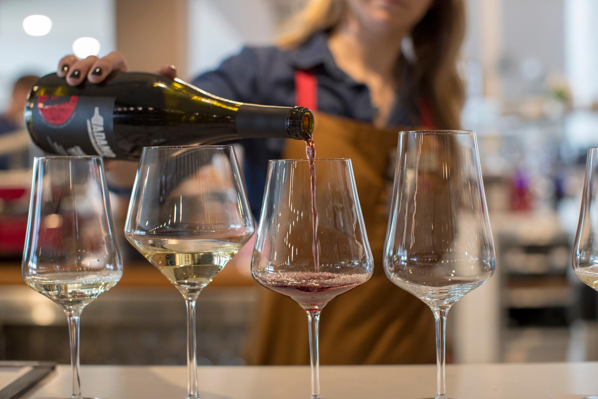 Adamo Estate Winery staff member pouring a red wine into a tasting flight of glasses in Hockley Valley, Ontario