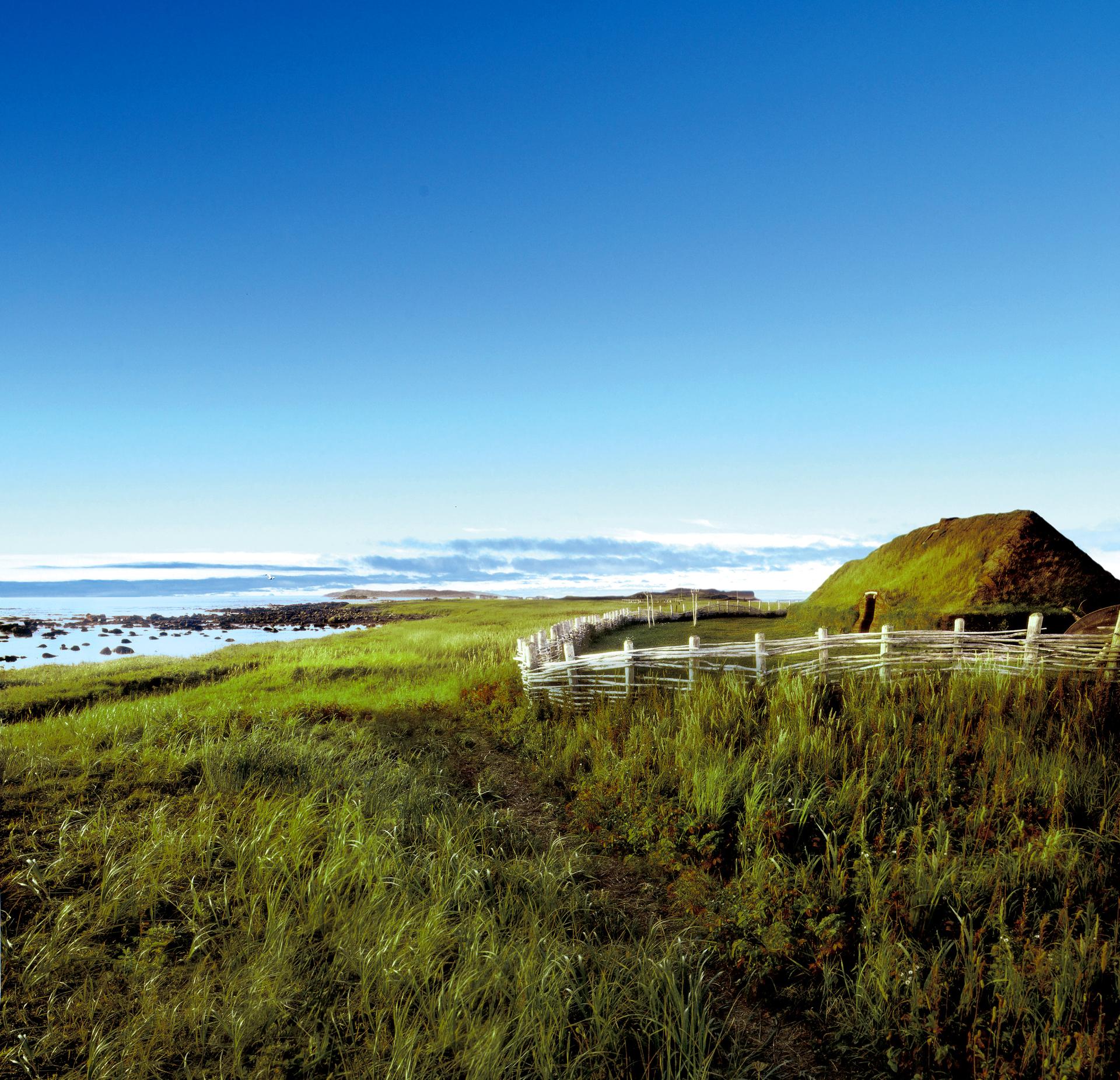 L'Anse aux Meadows Norse sod longhouse with a grass roof and wooden fence overlooking the coast at the tip of Newfoundland's Great Northern Peninsula
