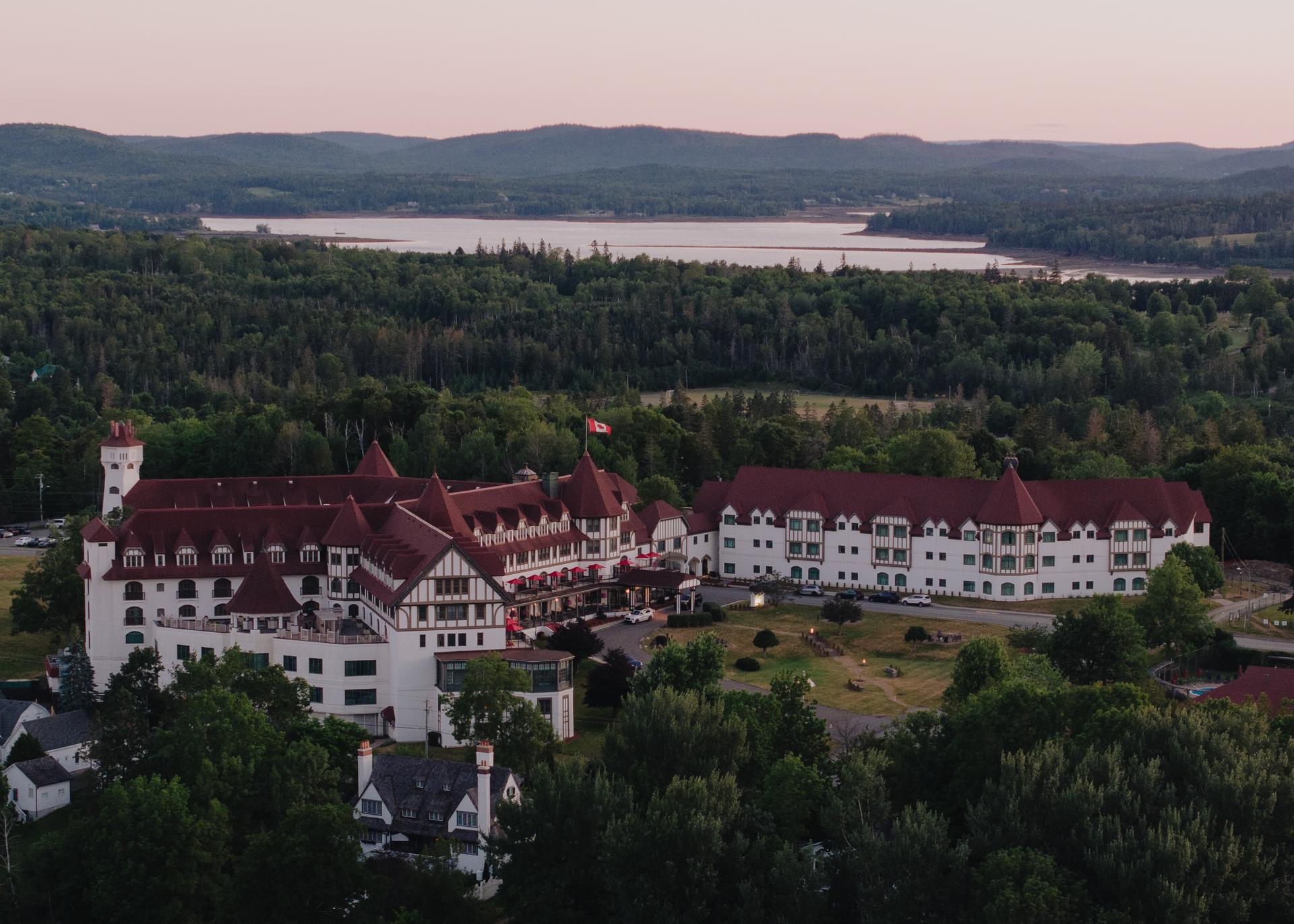 Aerial view of the Algonquin Resort in St. Andrews, New Brunswick, a Tudor-style resort with red rooftops set above the Bay of Fundy.
