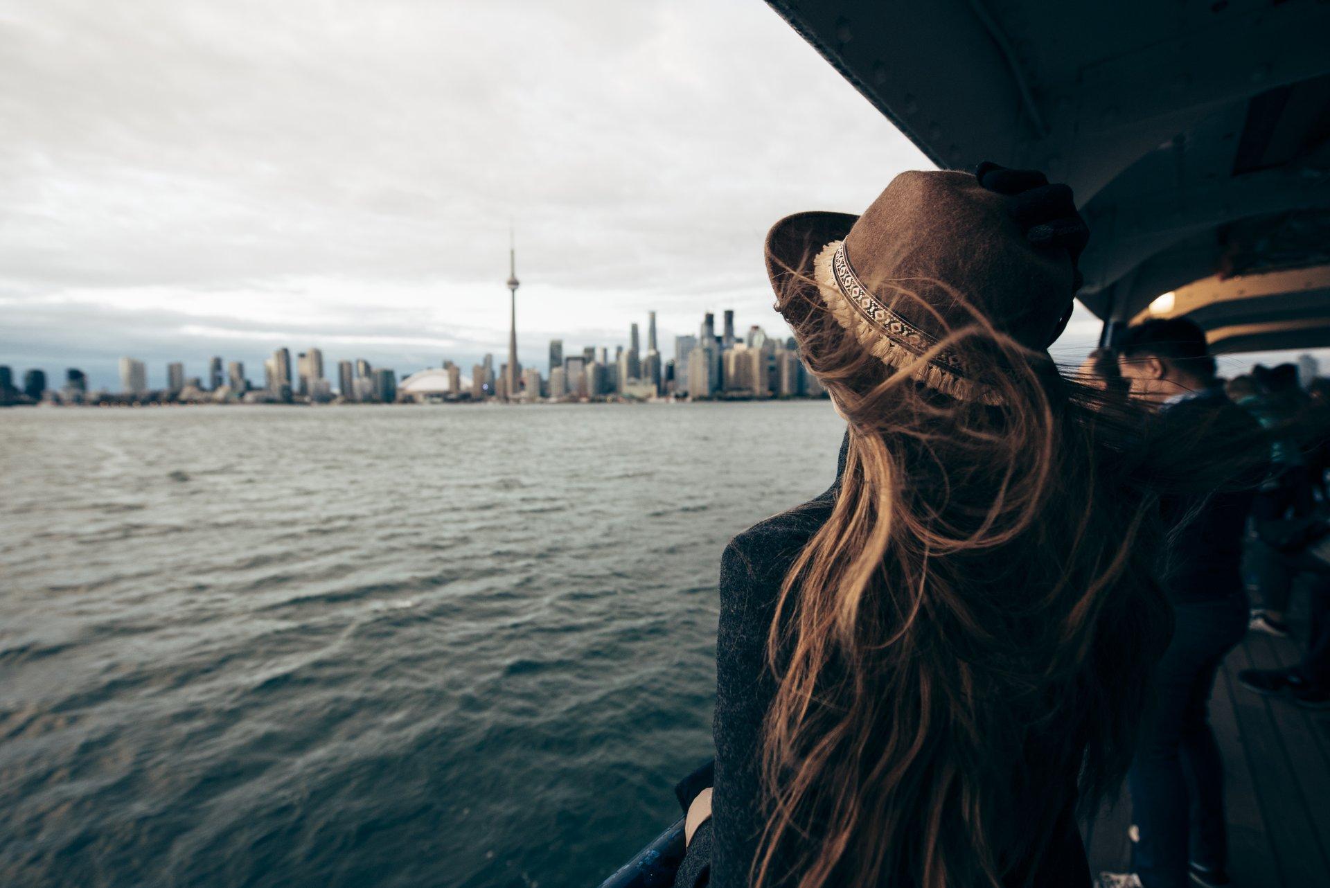 women on ferry with hair blowing in the wind looking at toronto