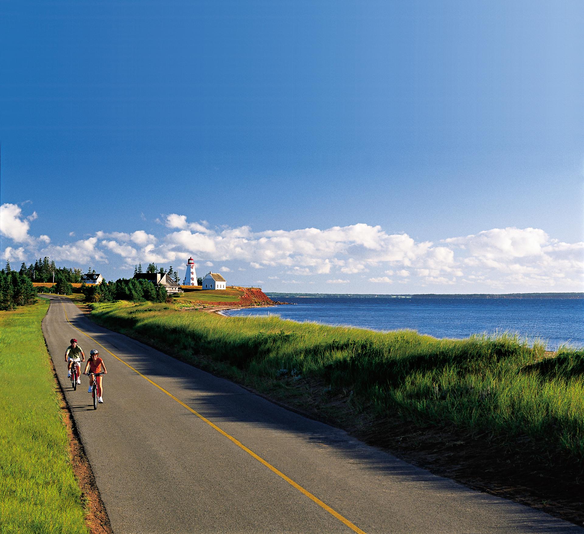 Two people cycling a paved bikeway with views of the ocean on Panmure Island Provincial Park, Prince Edward Island
