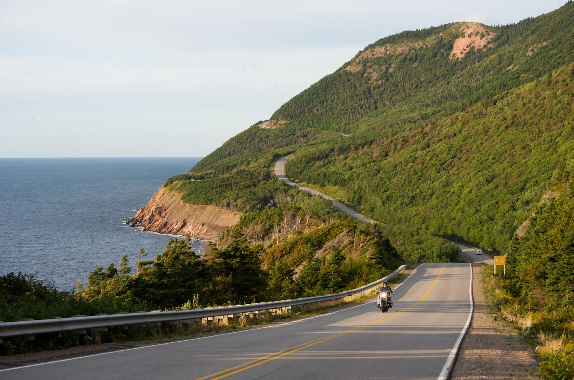 Person riding a motorcycle along the coast of Cape Breton Island