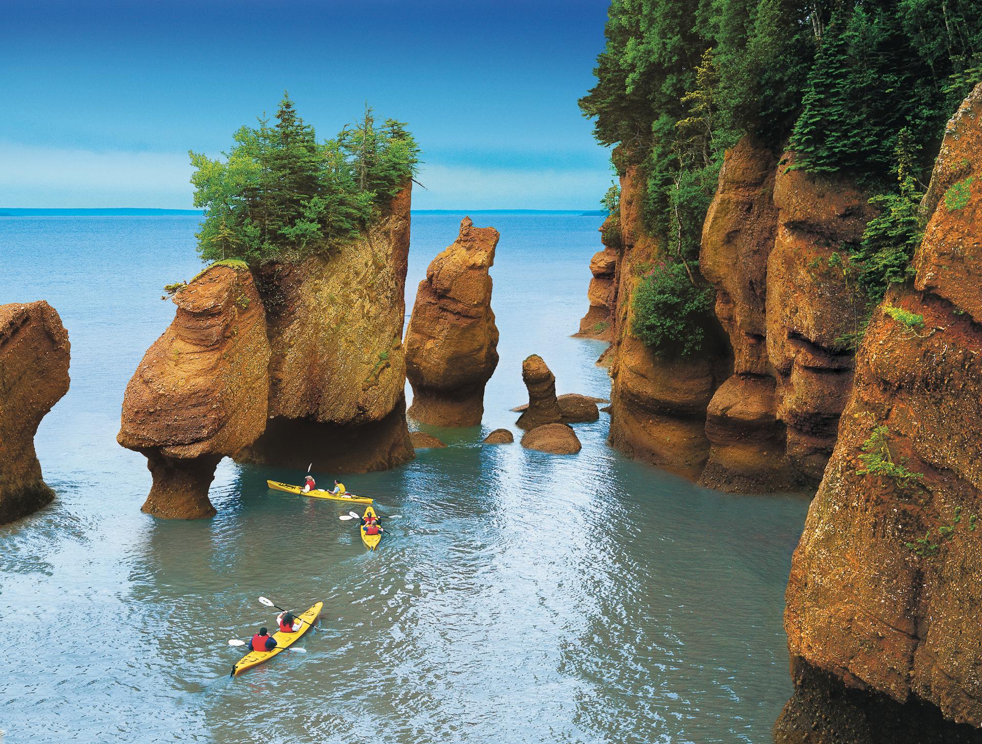 Two sets of kayakers paddling through Hopewell Rocks, Bay of Fundy