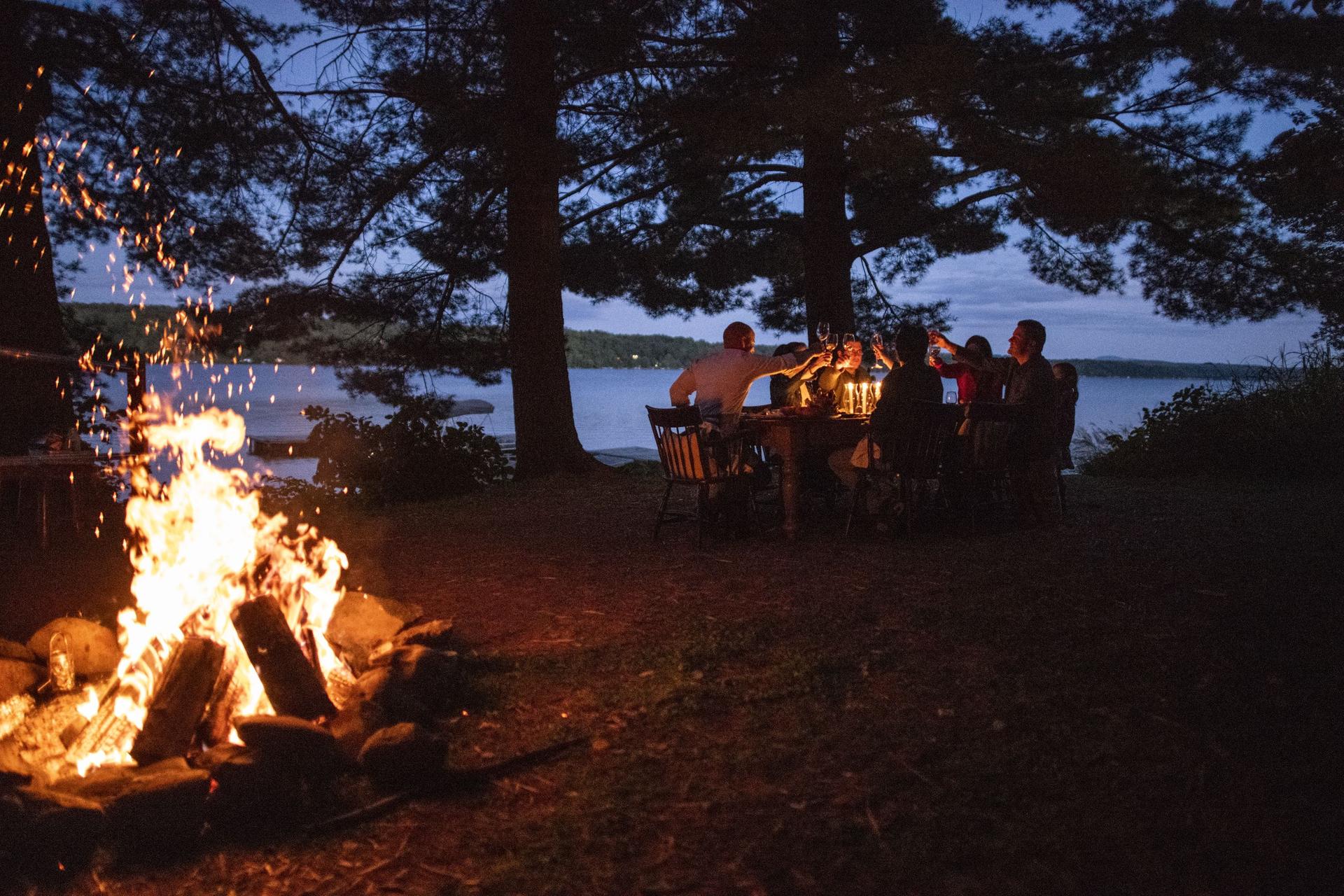 people sitting at a table by a camp fire