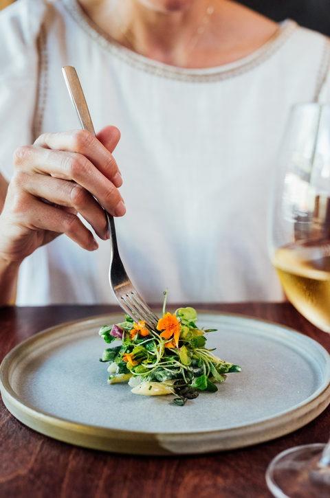 person holding fork above nicely placed green salad 