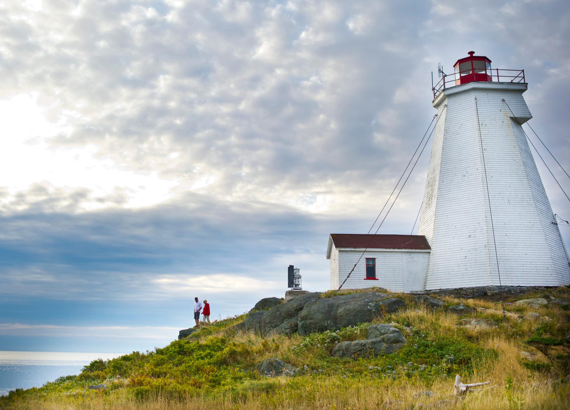 Two people taking in the view of the ocean from Swallowtail Lighthouse on Grand Manan, New Brunswick