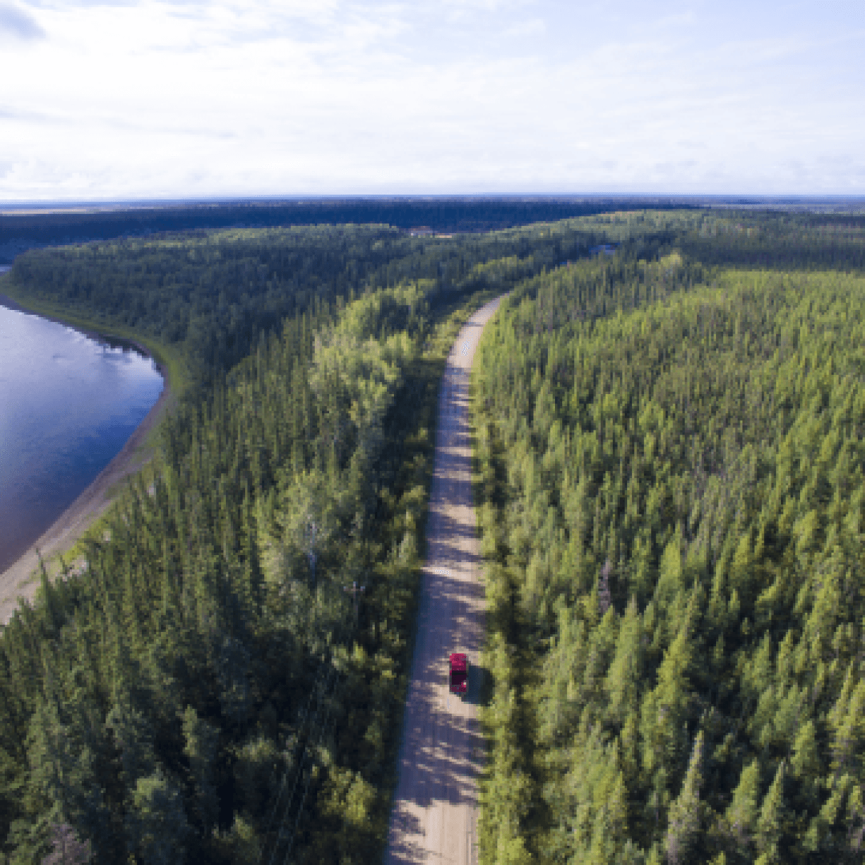 A tree-lined road beside a lake in the Northwest Territories