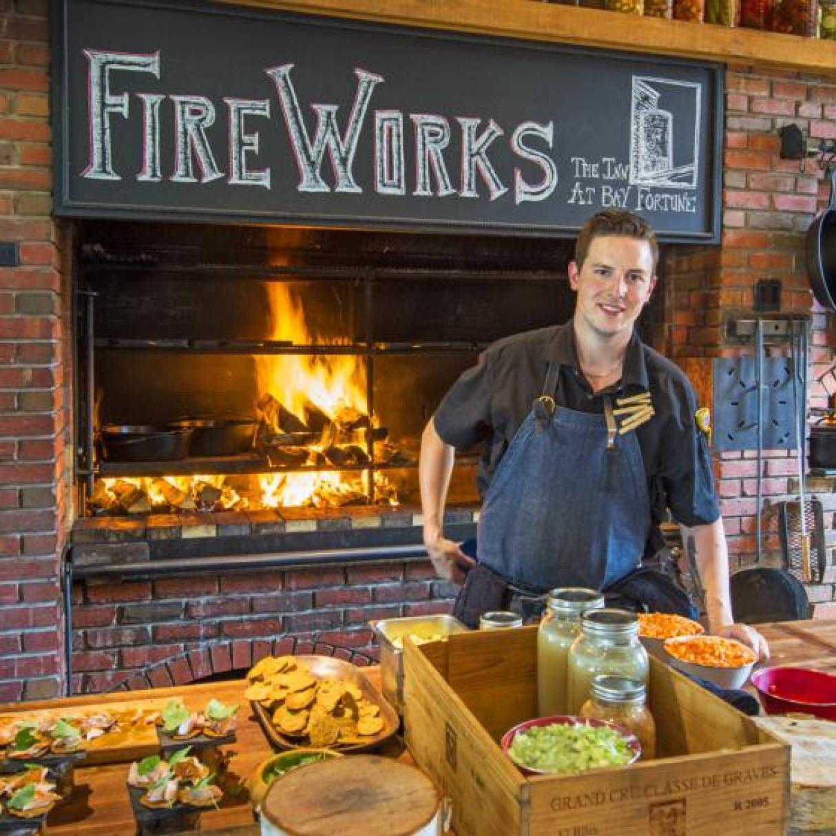 A chef cooks food over an open wood stove
