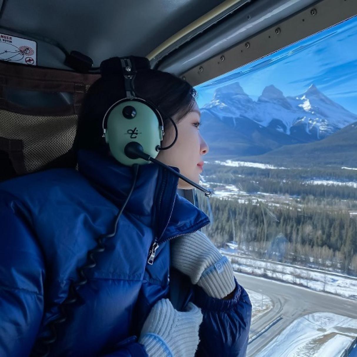 A tourist looks out a helicopter window