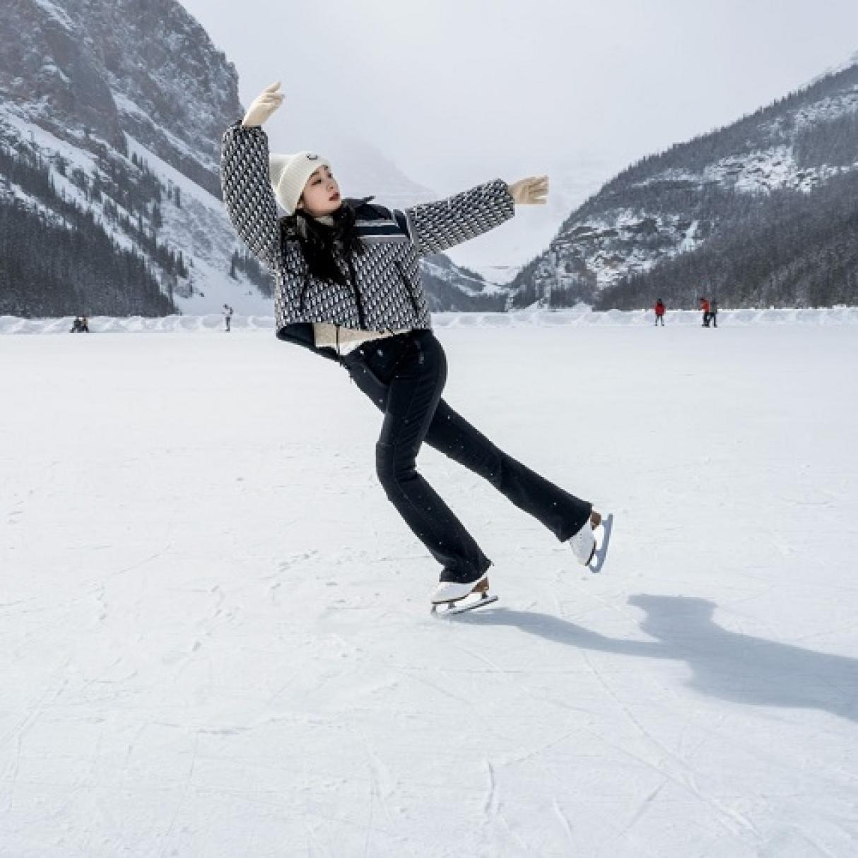 A figure skater on a lake beside mountains