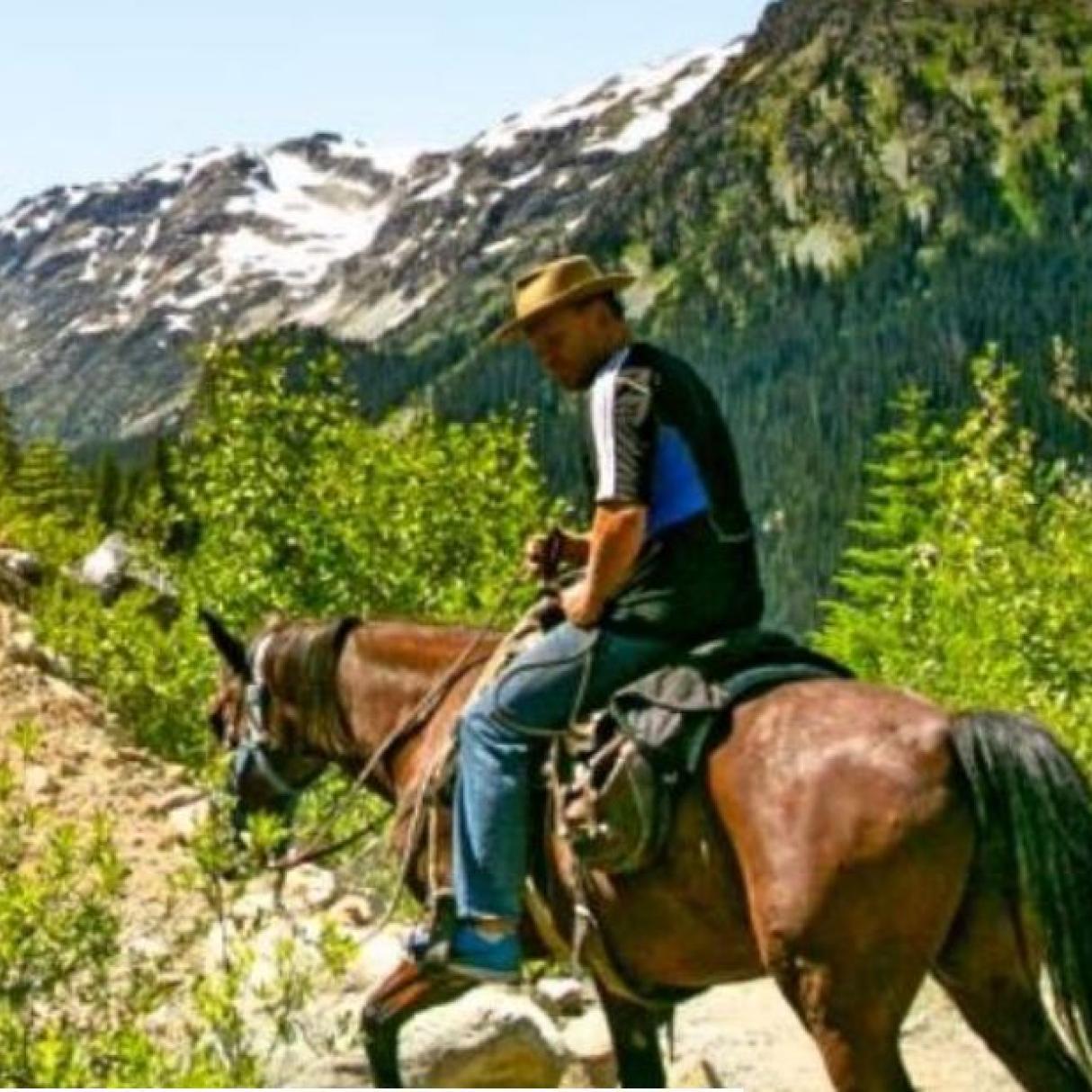 A horse and rider climb a mountain trail
