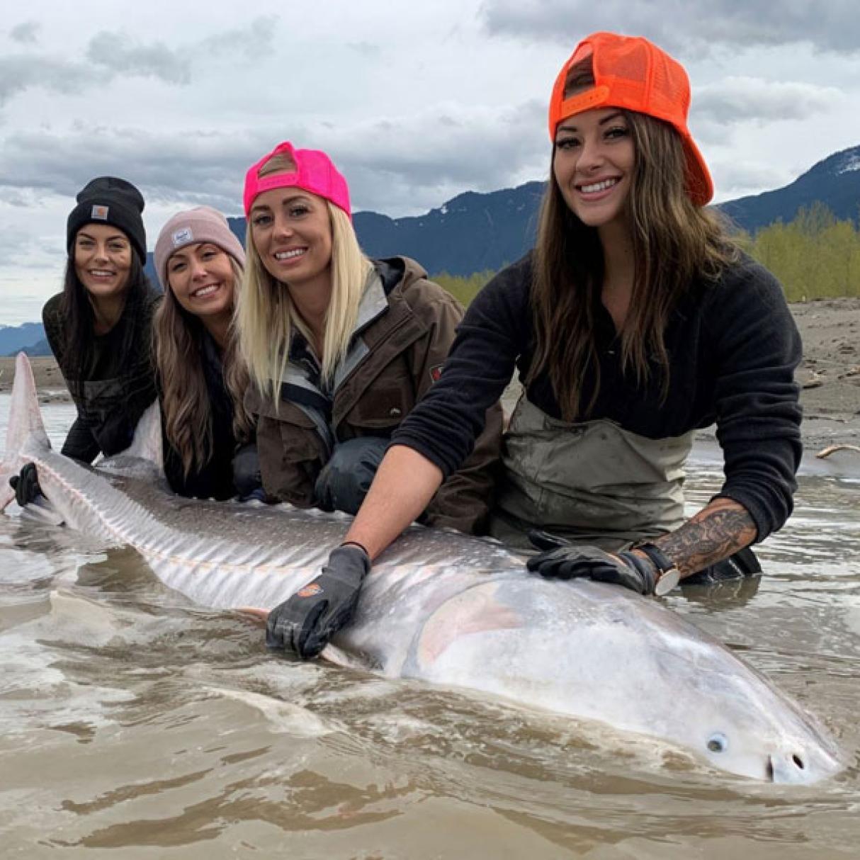 Group of women holding up a sturgeon