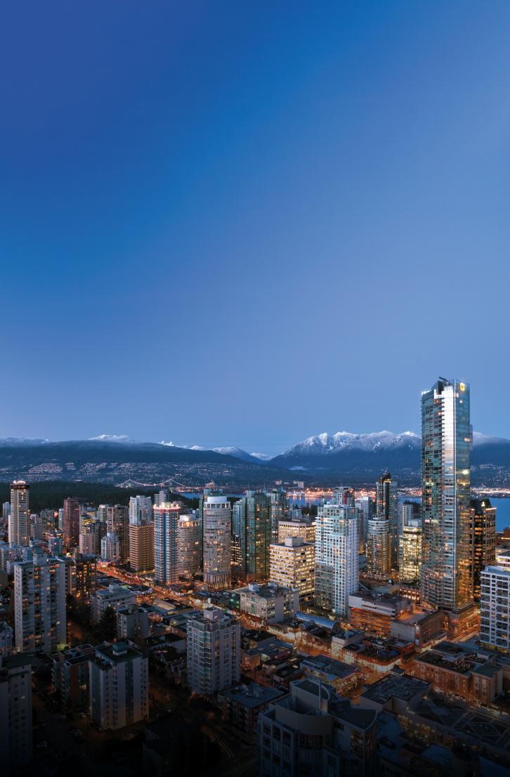 Aerial view of downtown Vancouver skyline at dusk with snow capped mountains in the background