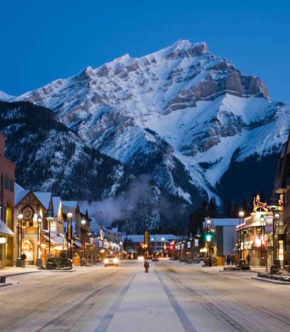 Banff, at night, with a view down a main road toward the snow-capped mountains