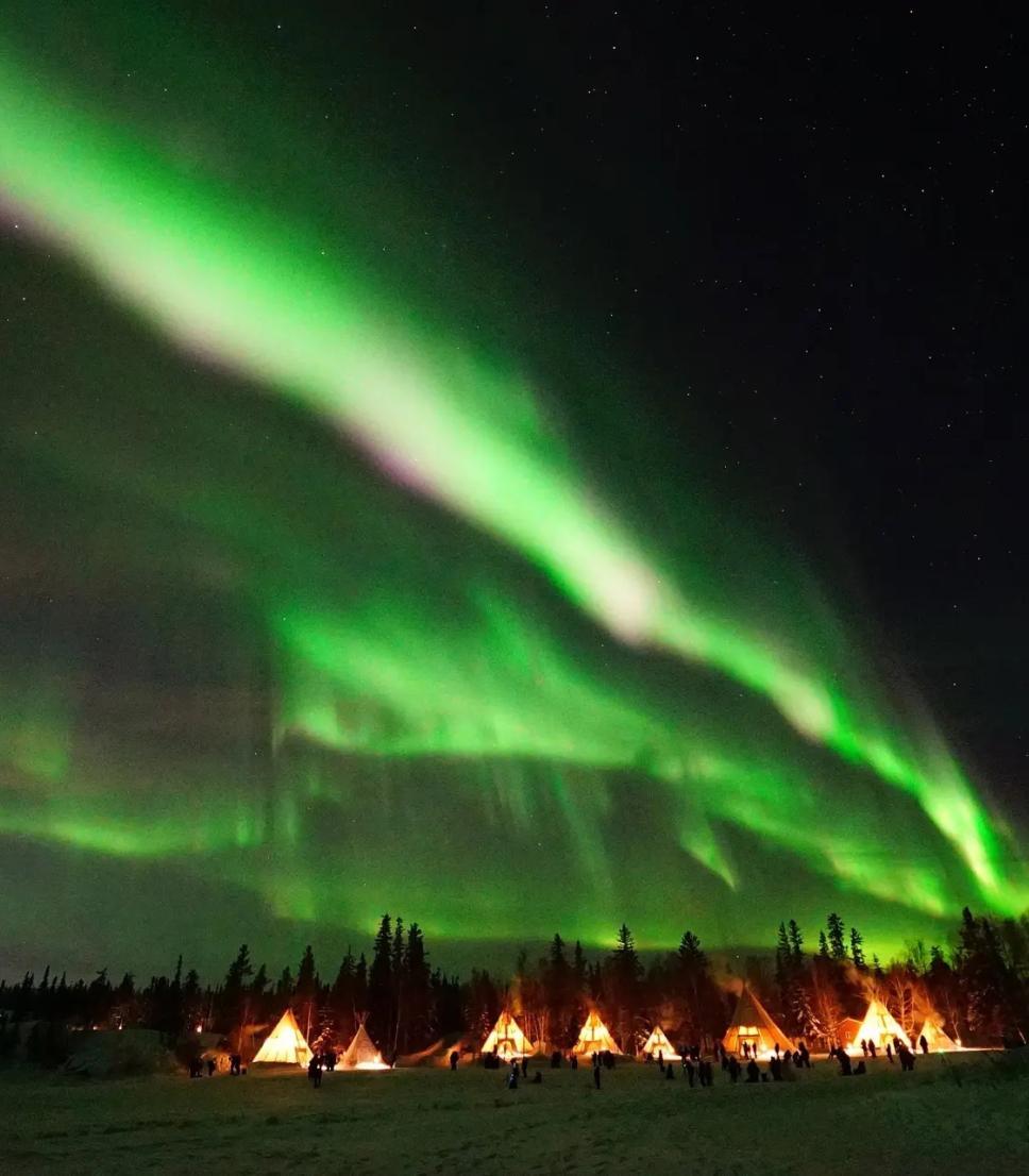 Aurora Village, teepees under vibrant green northern lights, Northwest Territories, Canada