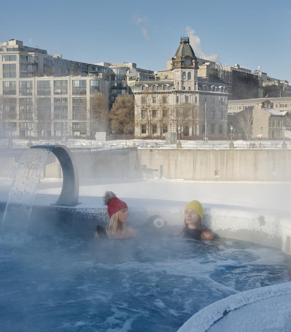 People soak in an outdoor thermal pool at Bota Bota spa in winter in the Old Port of Montreal